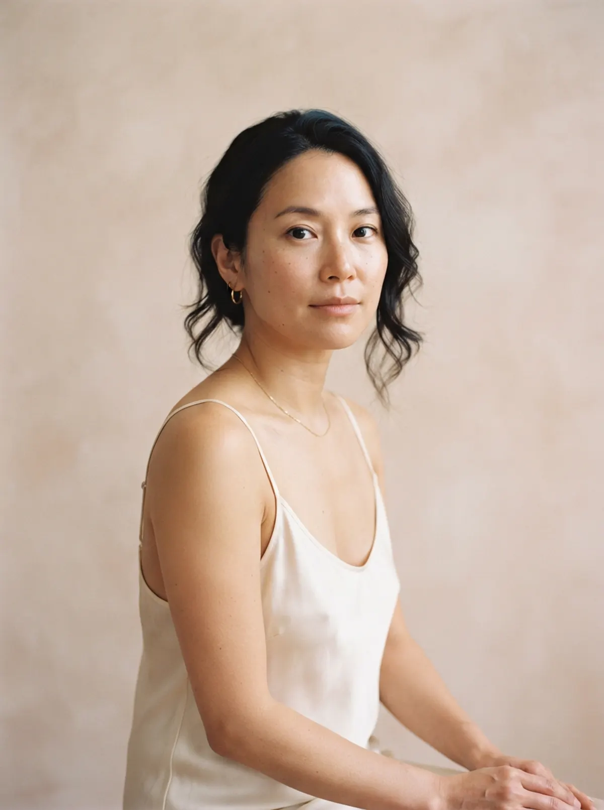 A woman seated in soft daylight, turning gently toward the camera.